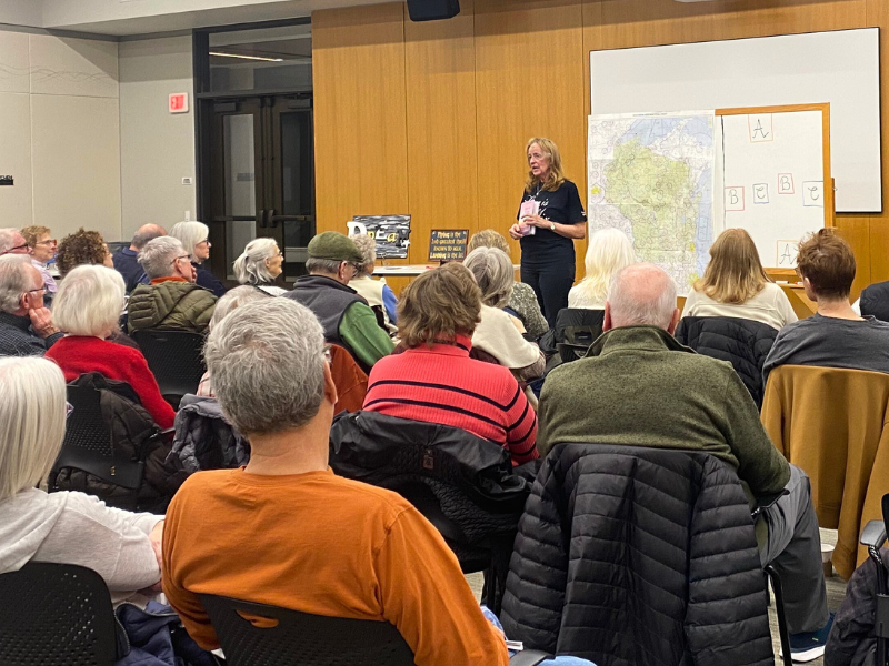 Photo of a woman holding a book in front of a crowd of people