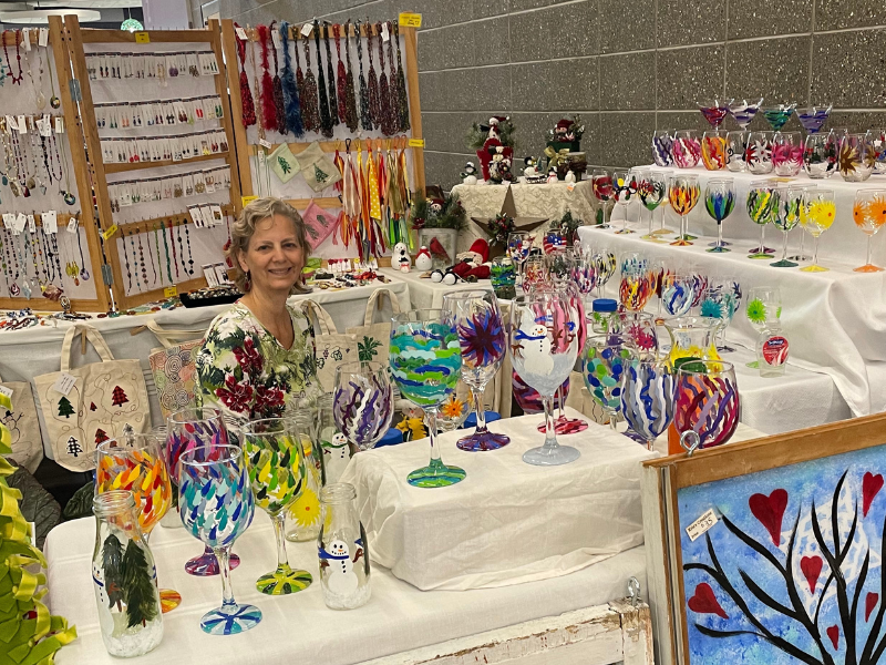Photo of a person sitting behind a table of colorful glassware