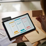 Tablet showing prices of a service with a person holding a credit card